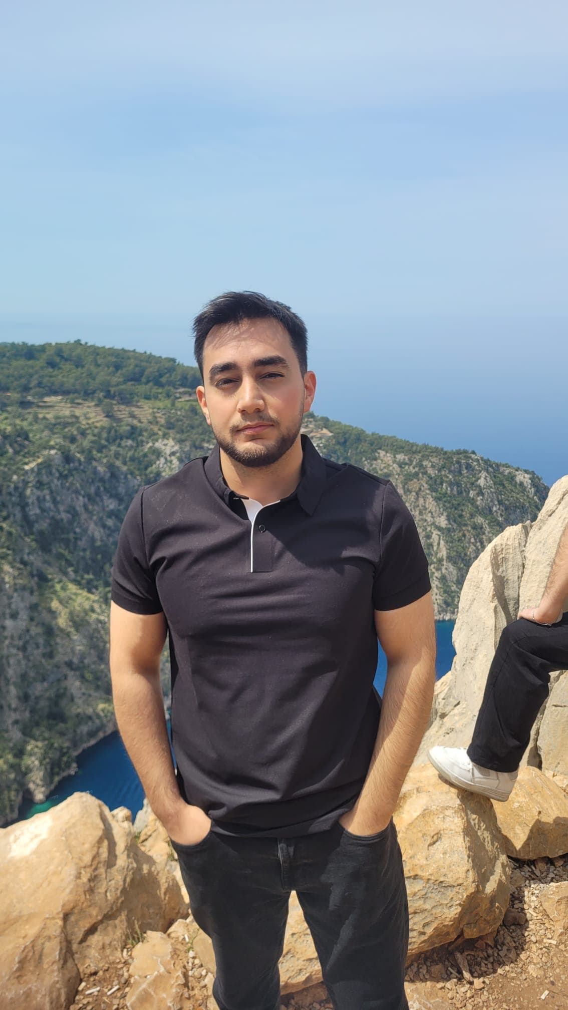 Samet Güçlü'nün portre fotoğrafı, tarihi taş yapı önünde çekilmiş.